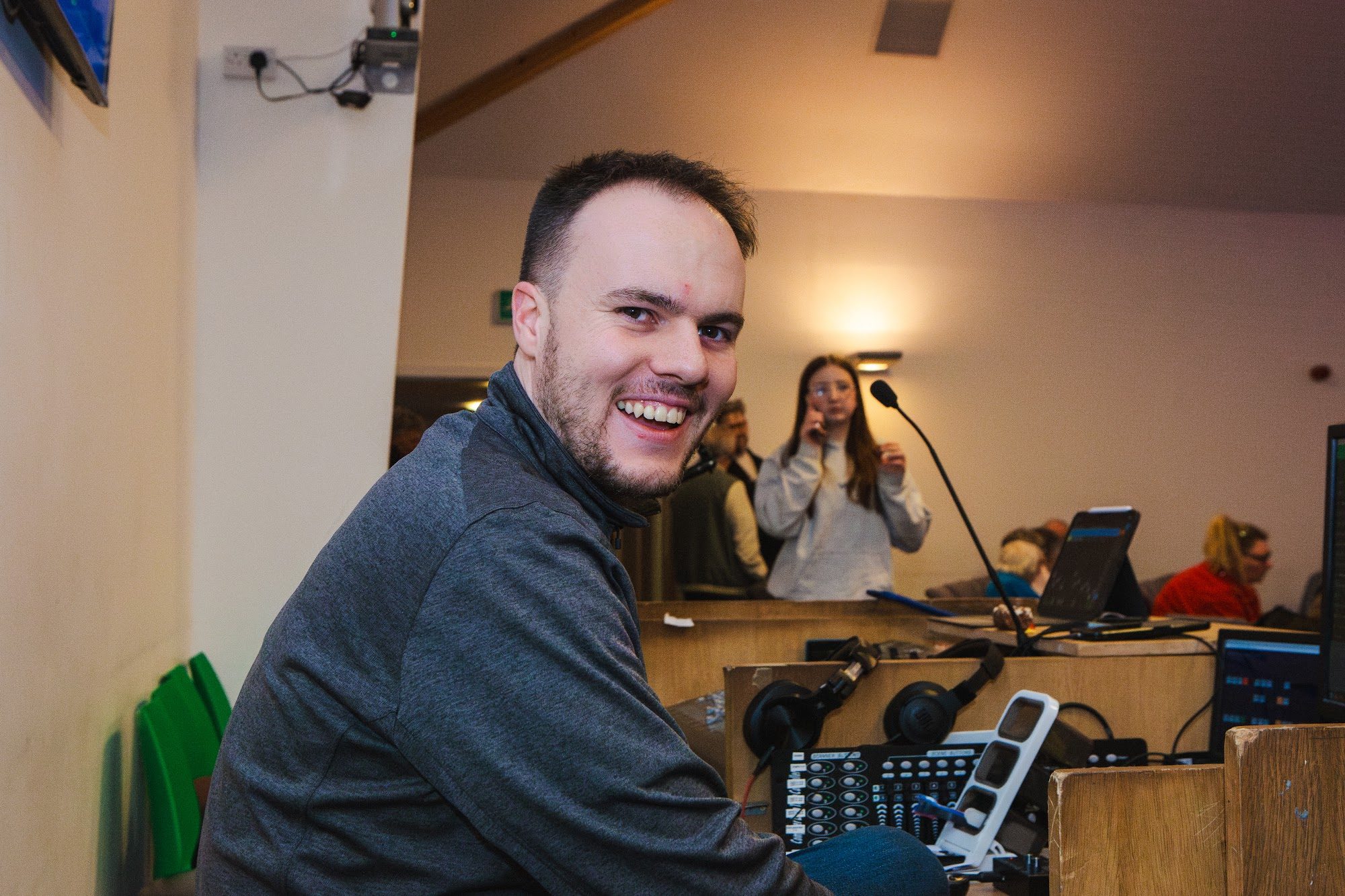 A smiling volunteer at the sound desk
